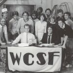 smiling students behind table with wcsf banner